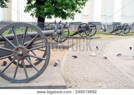 Vintage Cast Iron Cannon On A Carriage With Large Wheels. Against The Fence.