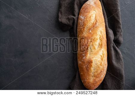 Top View Of Arranged French Baguettes In Paper Bag And Wheat On Dark Tabletop With Flour
