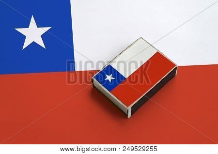 Chile Flag  Is Pictured On A Matchbox That Lies On A Large Flag.
