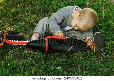 A Little Boy Dreams Of Becoming A Mechanic. The Guy Trains On A Bicycle. The Child Spins The Nuts On