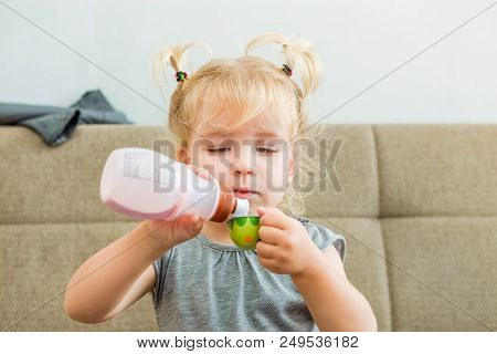 Close Up Cute Toddler Girl Pouring Natural Yogurt From Plastic Bottle To Toy Cup At Home . Healthy D