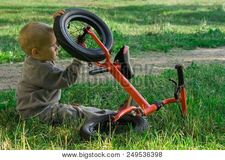 A Little Boy Dreams Of Becoming A Mechanic. The Guy Trains On A Bicycle. The Child Spins The Nuts On