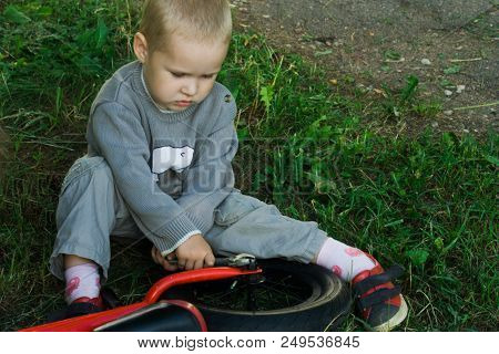 A Little Boy Dreams Of Becoming A Mechanic. The Guy Trains On A Bicycle. The Child Spins The Nuts On