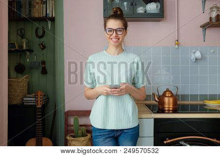 Closeup Photo Of Smiling European Female Staying At Home Alone Standing In Her Kitchen Communicating