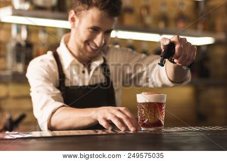 Special Equipment. Joyful Professional Barman Standing Behind The Bar Counter And Using A Culinary T