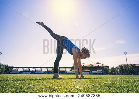 Yogi Woman Practicing Yoga Outdoor In The Park, One Legged Wheel Pose, Wearing Sportswear, Full Leng