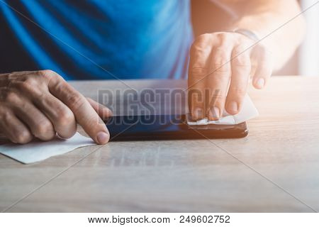 Man Cleaning Smartphone Screen With Cloth Before Applying Protective Cover Foil