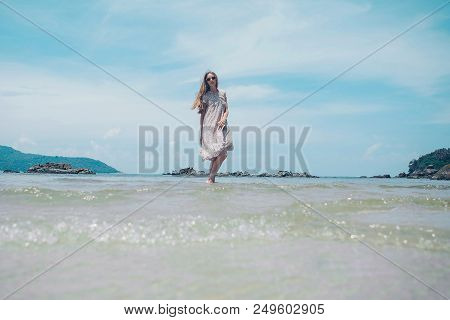 Handsome Girl On The Beach Background. Portrait Of A Woman In White Clothes On The Sea