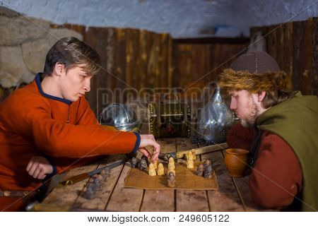 Two Men In Russian Ethnic Suit Playing Medieval Popular Strategy Board Game - Tafl. Folk, Competitio