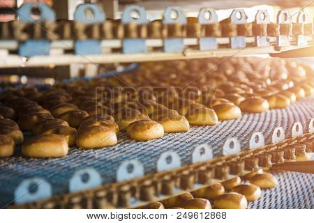 Cakes On Automatic Conveyor Belt Or Line, Process Of Baking In Confectionery Culinary Factory Or Pla