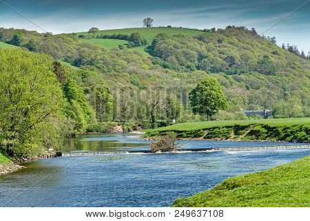 The River Lune Near Lancaster Flowing Through Rural Countryside Below Wooded Slopes.