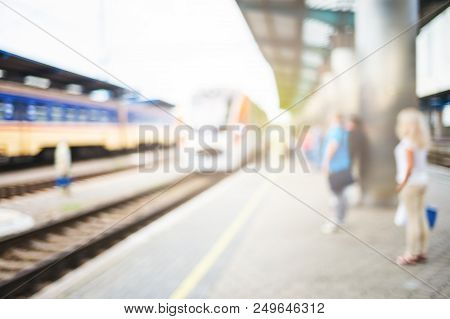 Blurred Image With Passengers Waiting Train On Platfom At Railway Station. Tourists With Baggage.