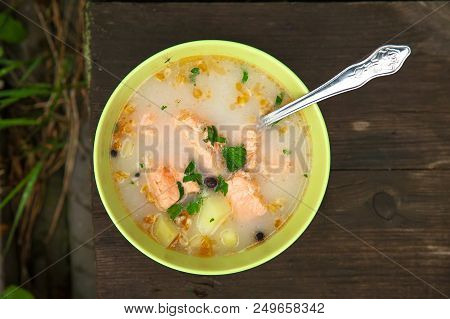 Fish Soup On An Old Wooden Table In Nature Among The Green Grass