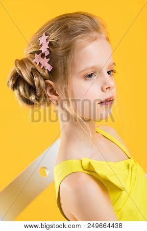 Portrait Of A Teenage Girl In A Yellow Dress. At The Child Hair Are Collected In A Fascicle And Are 