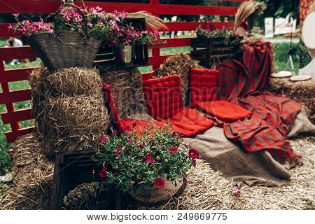 Rustic Photo Booth. Rural Photo Zone With Haycocks, Hay Chairs And Flowers Arrangement At Wedding Re