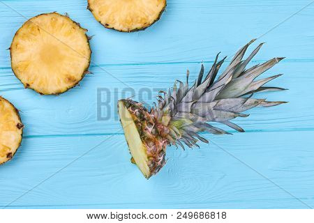 Freshly Cut Circle Slices Of Pineapple. Flat Lay Pineapple Crown On Blue Wooden Surface. Healthy Eat