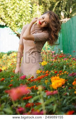 Happy Woman In A Dress Standing In A Bed Of Flowers