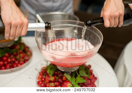 Beverage With Ice Cubes. Pouring Champagne. Mint And Fruit Are Out Of Focus