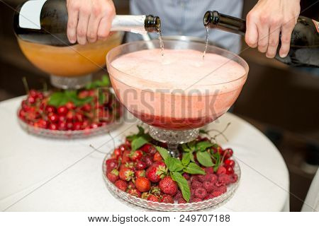 Beverage With Ice Cubes. Pouring Champagne. Mint And Fruit Are Out Of Focus
