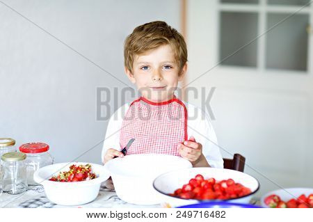 Little Blond Kid Boy Helping And Making Strawberry Jam In Summer. Funny Child Cleaning Berries And P
