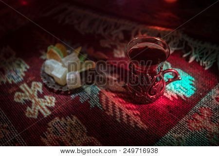 Arabian Tea In Glass With Eastern Snacks On A Carpet On Dark Background With Lights And Smoke. Easte