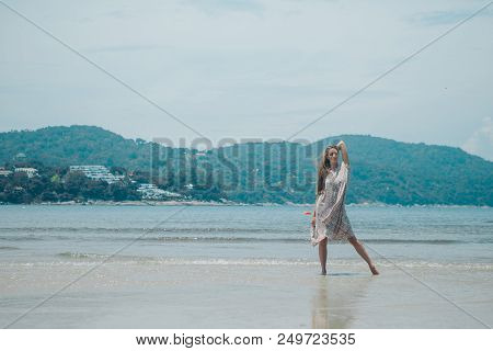 Handsome Girl On The Beach Background. Portrait Of A Woman In White Clothes On The Sea