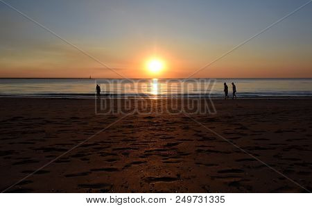 People Enjoy The Sunset At Mindil Beach. The Sun Casts Orange Shades Across An Evening Sky At Mindil
