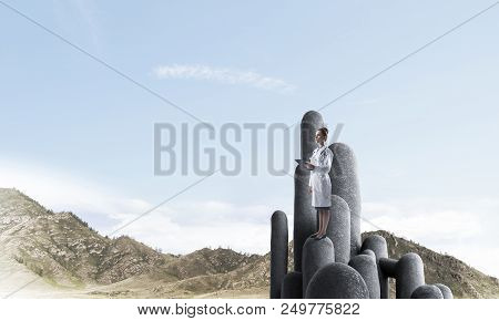Young Female Doctor With Folder In Hands Satnding On Stone Column