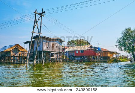 The Wooden Houses On Stilts And Old Timber Utility Pole, Supporting Wires On The Foreground On Inle 