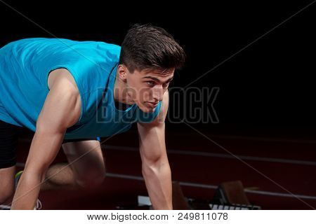 Sprinter Leaving Starting Blocks On The Running Track In Front Of Big Modern Stadium With Lights And