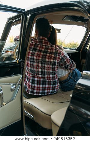 Couple, Man And Woman Are Sitting In The Car, The Guy Is Hugging The Girl. Cinema. Check Shirt And W