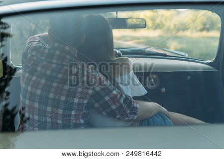 Couple, Man And Woman Are Sitting In The Car, The Guy Is Hugging The Girl. Traveling Together. Check