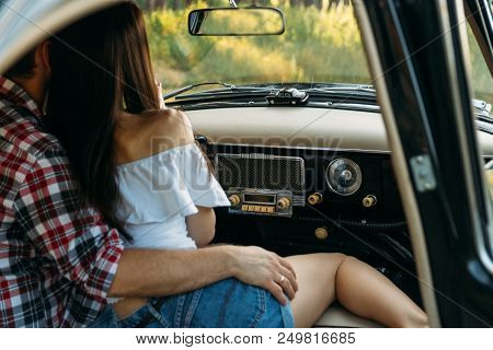 Couple, Man And Woman Are Sitting In The Car, The Guy Is Hugging The Girl. Date. Check Shirt And Whi