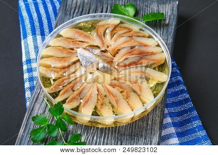 Marinated Herring In Oil On A Wooden Board On A Gray Dark Table. Snack