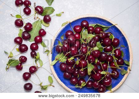 Top View Of Ripe Red Cherry In The Blue Plate And On The Table