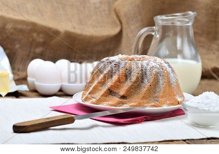 Homemade Bundt Cake Sprinkled With Sugar, Milk And Eggs In Background, Still Life With Marble Cake O