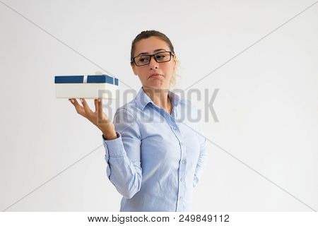 Puzzled Female Manager Disappointed About Gift Size And Weight. Young Business Woman Looking At Pres