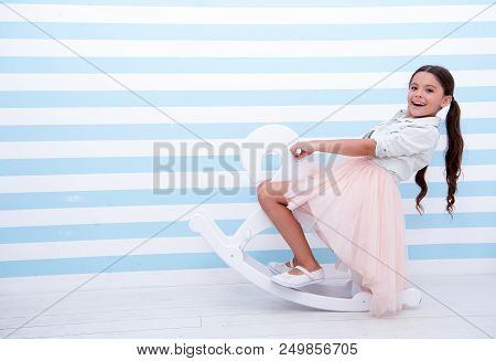 Have Fun. Girl Child Rides White Rocking Horse On Striped Background. Child Girl Happy Face With Lon