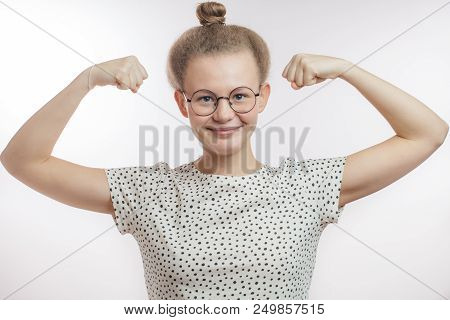 Fair-haired Girl Showing Braws. Young Slim Woman Is Giving Her Biceps A Flex To Impress The Men. Ben