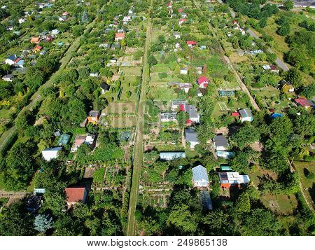 Multiple Allotment Gardens With Little Arbors, Greenhouses, Trees And Bushes, Aerial View.