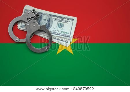 Burkina Faso Flag  With Handcuffs And A Bundle Of Dollars. The Concept Of Breaking The Law And Thiev
