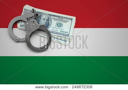 Hungary Flag  With Handcuffs And A Bundle Of Dollars. The Concept Of Breaking The Law And Thieves Cr