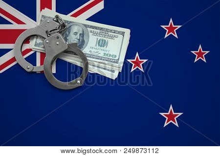 New Zealand Flag  With Handcuffs And A Bundle Of Dollars. The Concept Of Breaking The Law And Thieve