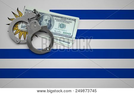Uruguay Flag  With Handcuffs And A Bundle Of Dollars. The Concept Of Breaking The Law And Thieves Cr