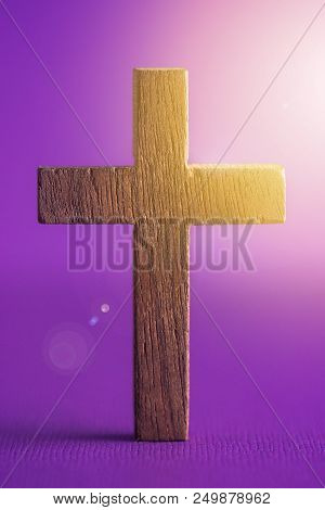 A Simple Wooden Cross On A Purple Background