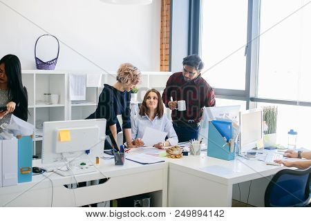 Grinning Woman Looking At Her Blond Co-worker And Giving An Account To Her Mixed Race Employees