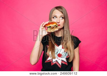 Front View Of Sadly Young Girl Looking At Side And Thinking Eating Tasty Humburger Or No. Pretty Wom