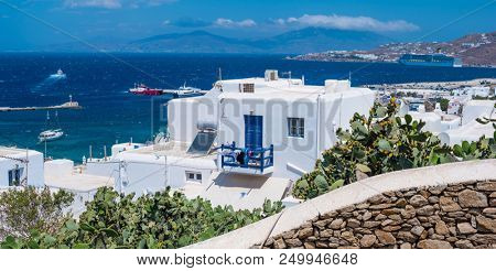 Panoramic view on decorative cactus plants in front of Greek style lassical white houses against the sea and blue sky