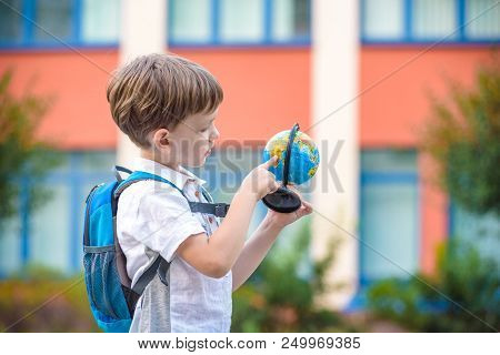 Portrait Of A Little Boy Holding A Globe. Travel Concept