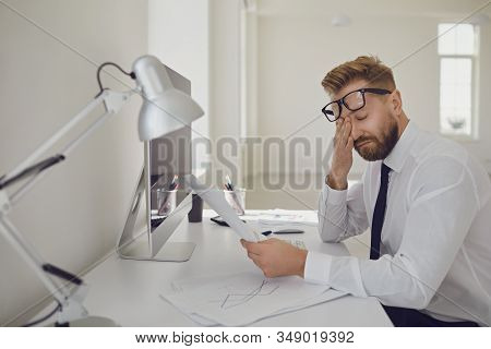 Exhausted Tired Worker At The Workplace Covered His Face With His Hands In The Office